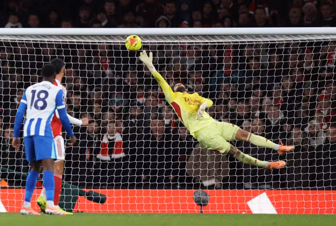 David Raya bay người cản cú đá của Yankuba Minteh. Ảnh: Reuters