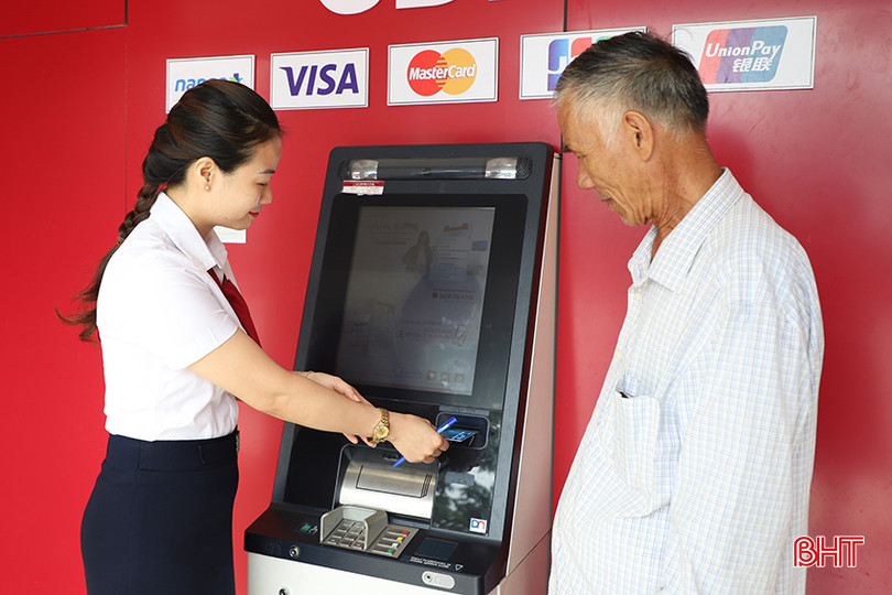 Nhân viên Agribank Chi nhánh huyện Can Lộc hướng dẫn ông Lương Hữu Bát sử dụng các dịch vụ ngân hàng qua thẻ. 2.jpg