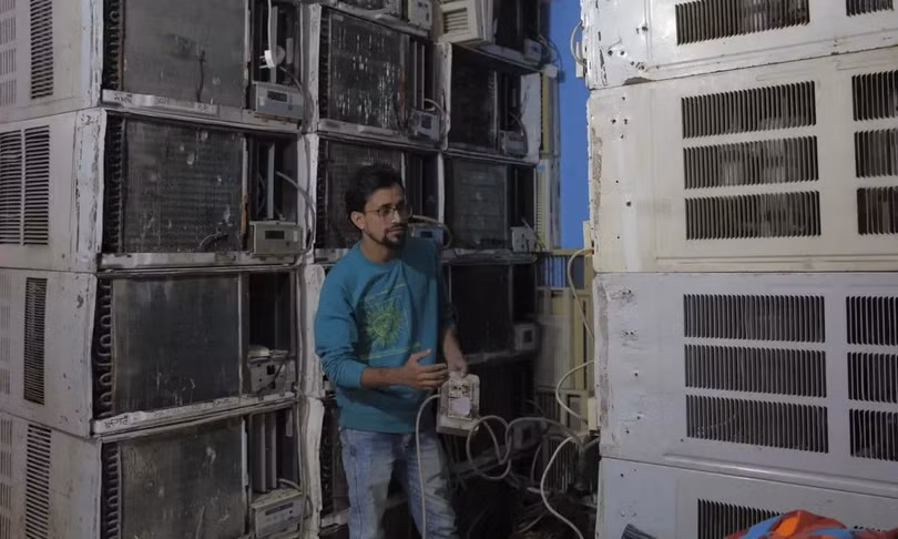Mohammad Adil Khan kiểm tra máy điều hòa tại cửa hàng cho thuê của mình ở Delhi. Ảnh: Aakash Hassan/ Guardian.