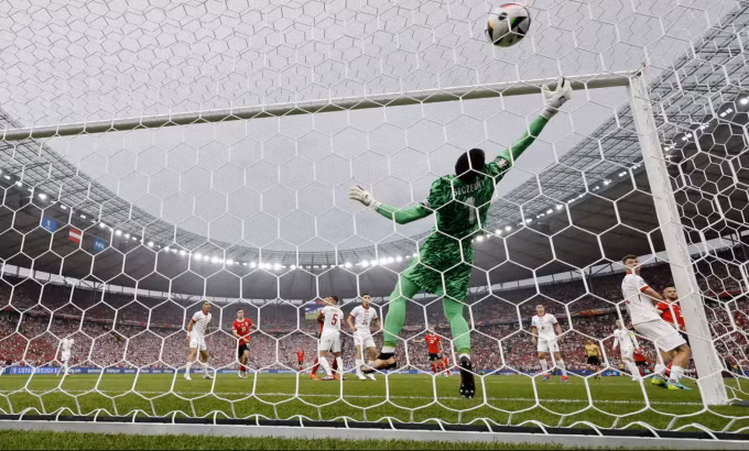 Thủ môn Wojciech Szczesny (áo xanh) bất lực trước cú đánh đầu cự ly gần của Gernot Trauner (áo đỏ phải) mở tỷ số trong trận Ba Lan thua Áo 1-3 ở lượt hai bảng D Euro 2024. Ảnh: EPA
