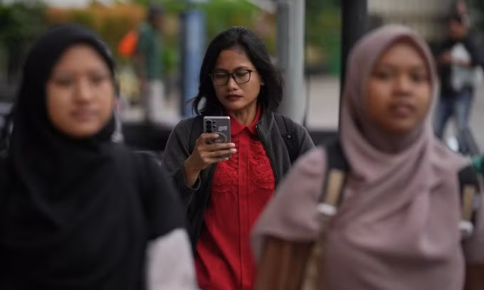Một phụ nữ sử dụng điện thoại trên đường phố thủ đô Jakarta, Indonesia, ngày 6/3. Ảnh: AP