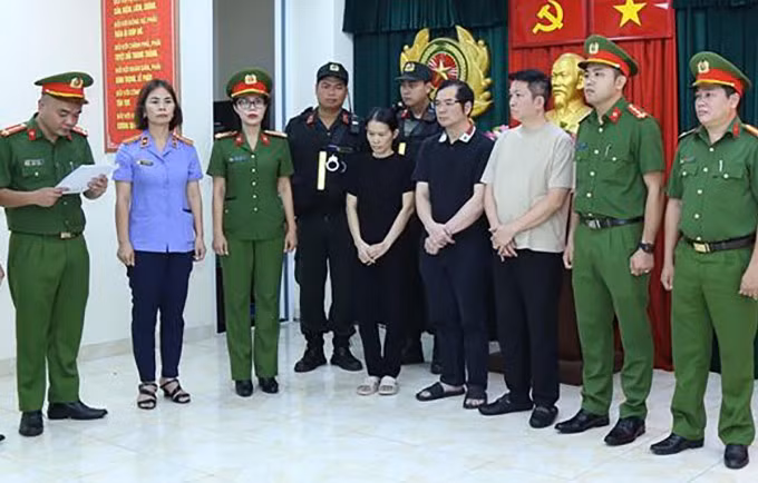Các bị can (giữa) nghe công an đọc lệnh bắt. Ảnh: Thái Hà