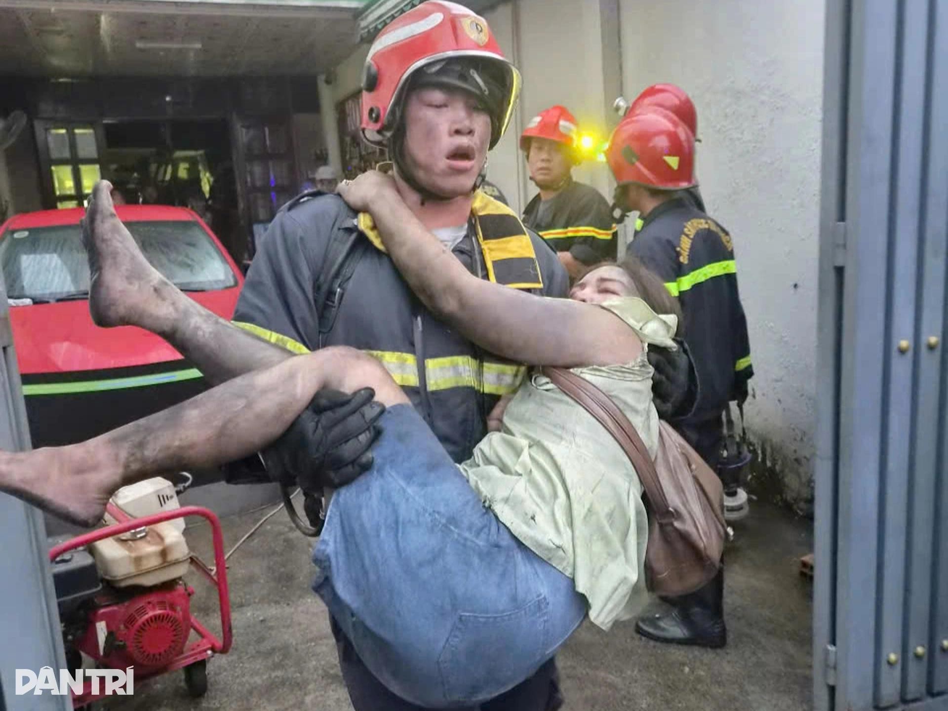 Cảnh sát tìm thấy và giải cứu một người phụ nữ, bế nạn nhân chạy ra ngoài an toàn (Ảnh: Thuận Thiên).