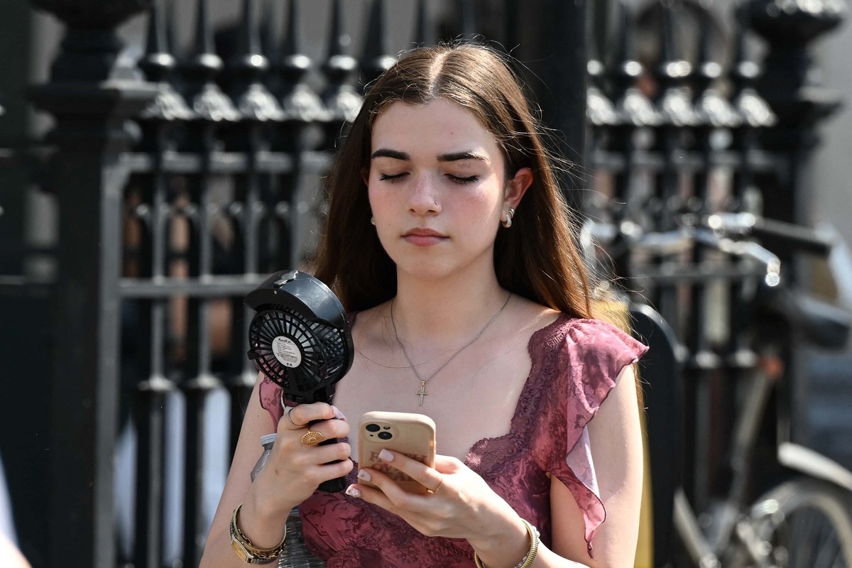 Người qua đường tìm bóng râm, che ô hay dùng quạt cầm tay trên đường phố London ngày 22/6.