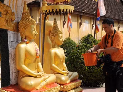Giao thừa trong Tết Lào được hiểu là sau thời gian làm lễ tắm Phậtt. Vị trông coi chùa tháp That Luông (Viên Chăn) tắm vào buổi sáng trước khi sắp lễ. Lễ tắm Phật. Người Lào thường dùng nước để tắm cho tượng Phật hoặc ban nước thơm cho các du khách tắm tượng Phật trong các ngôi chùa. Biểu diễn trên đường phố. Tất cả các cuộc vui chơi, lễ hội được tổ chức theo truyền thống tôn giáo. Vòi phun nước công cộng cũng trở thành nơi vầy nước của trẻ em Các sư đi té nước và bị té nước trên đường phố. Ai cũng ướt sũng. Té nước để cầu may mắn, bình yên cho cả năm. Hoa Chămpa và hoa Muồng vàng là hai loài hoa phổ biến vào dịp Tết Lào. Hoa Chăm pa được kết vòng đeo cổ hoặc cài lên tóc, hoa muồng vàng được treo trên cửa kính ôtô, xe máy và cả xe lam.