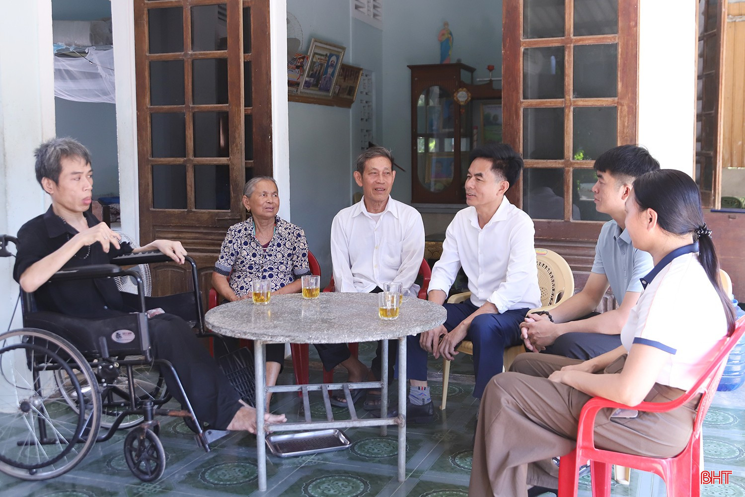 Cán bộ địa phương động viên, chia sẻ niềm vui với gia đình ông Lê Văn Minh (thứ ba từ trái sang) khi con trai ông được hỗ trợ xây dựng nhà ở.