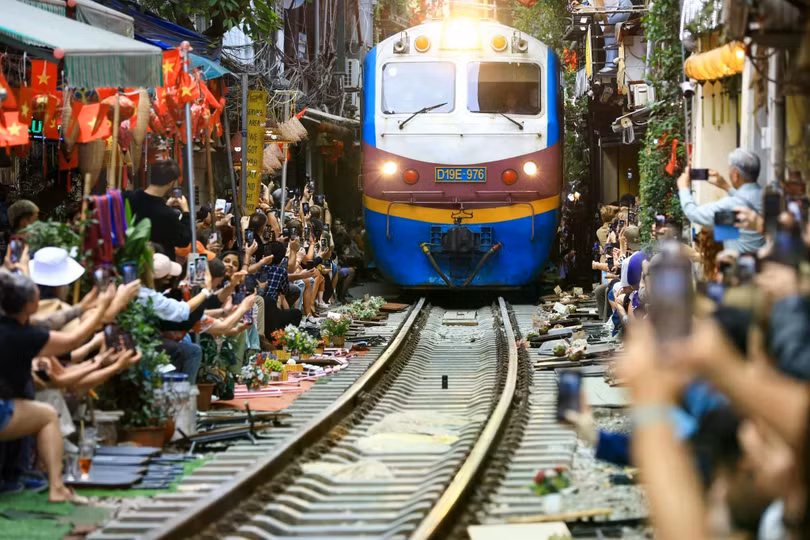Du khách ngồi sát đường ray, đồng loạt quay phim, chụp ảnh khi đoàn tàu đi qua. Ảnh: Trần Hiền.