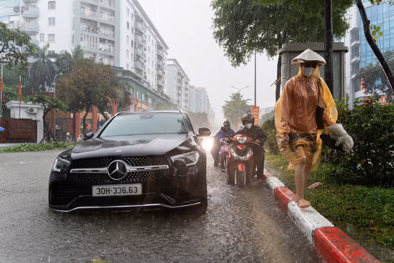 Lề đường ngập sâu, nhiều phương tiện phải di chuyển men theo dải phân cách ở giữa. Dù vậy, không ít người vẫn lựa chọn dắt bộ để tránh bị nước vào động cơ. Ảnh: Trần Hiền.