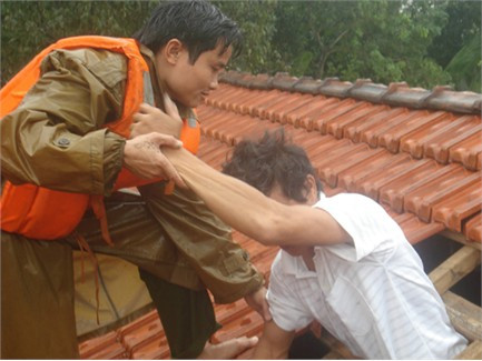 Thiếu tá Ngô Đức Ninh (Công an huyện Vũ Quang) dỡ ngói cứu một người dân xóm Hương Hòa, xã Đức Hương (Vũ Quang) thoát khỏi lũ dữ (ảnh chụp 17/10/2010)