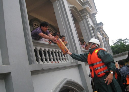 Phó Chủ tịch UBND tỉnh Lê Đình Sơn phát mỳ tôm và nước uống cho bà con giáo dân Giáo xứ Đông Hải (Gia Phố) đang đến tránh lũ tại nhà thờ Người dân xóm 14, xã Gia Phố phải dỡ ngói để vào nhà