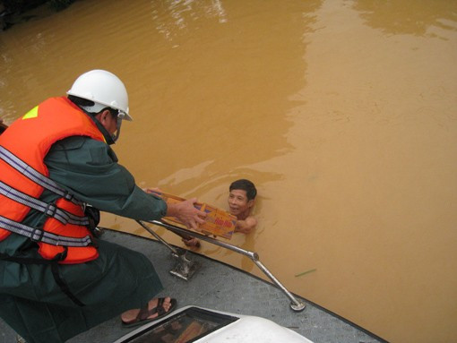 Phó Chủ tịch UBND tỉnh Lê Đình Sơn phát mỳ tôm và nước uống cho bà con giáo dân Giáo xứ Đông Hải (Gia Phố) đang đến tránh lũ tại nhà thờ Người dân xóm 14, xã Gia Phố phải dỡ ngói để vào nhà