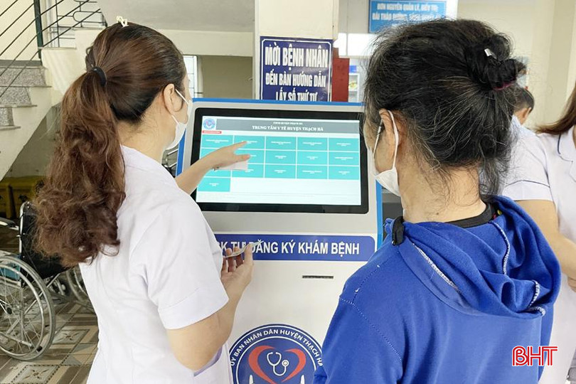 Nhân viên Trung tâm Y tế huyện Thạch Hà hướng dẫn người dân thực hiện đăng ký khám bệnh tại máy tra cứu thông tin KIOSK. thach ha 3A.jpg