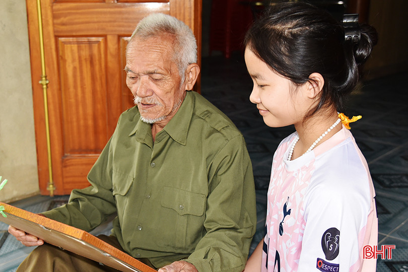 Ông Vi Xuân Cảnh kể cho cháu nội nghe về nguồn cội dân tộc mình qua những tấm ảnh cũ. DSC_3213.JPG