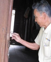 Ông Nguyễn Văn Xuân bên cánh cửa bị cạy phá.