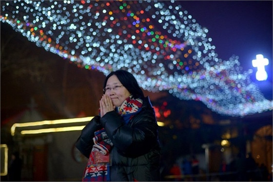 Một phụ nữ ở Bắc Kinh cầu nguyện trong đêm Giáng sinh. Ảnh AFP