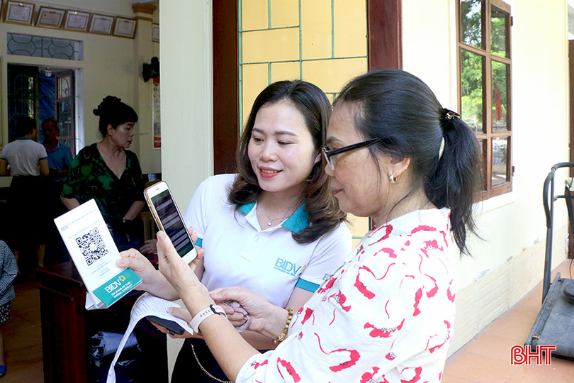 Cán bộ BIDV Hà Tĩnh hướng dẫn người dân quét mã QR thực hiện nộp thuế sử dụng đất phi nông nghiệp không sử dụng tiền mặt. 4.jpg