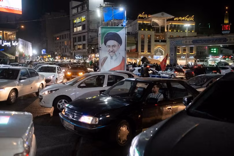 Dòng xe lưu thông qua tấm biển in chân dung Lãnh tụ Tối cao Iran Mojtaba Khamenei trong cuộc tuần hành ủng hộ chính phủ ở Tehran tối 21/10. Ảnh: AFP