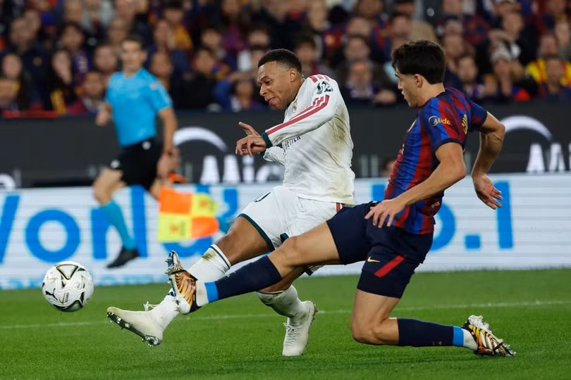 Tiền đạo Kylian Mbappe (trái) của Real Madrid dứt điểm trước sự truy cản của hậu vệ Pau Cubarsi bên phía Barca trong trận đấu tại La Liga trên sân Camp Nou, Barcelona, Tây Ban Nha, ngày 25/10/2026. Ảnh: AP