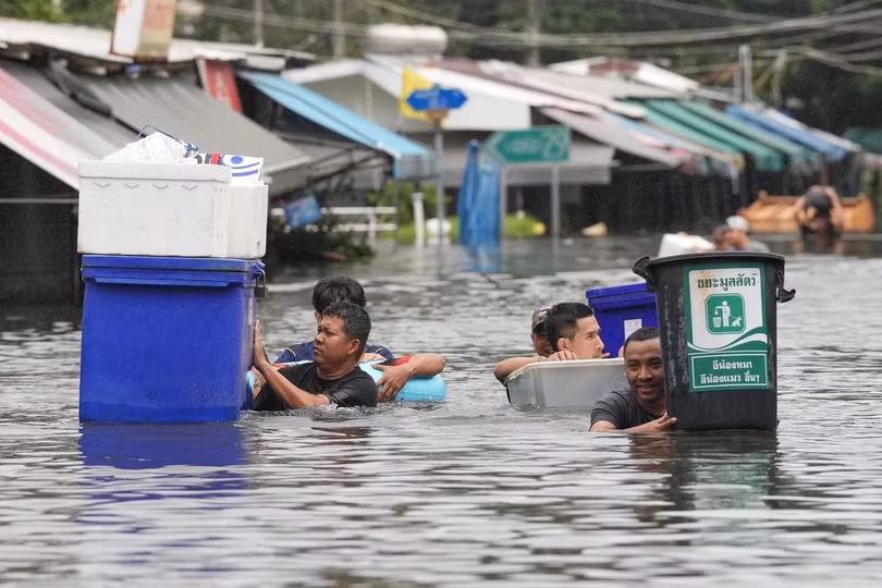 Người dân di chuyển qua vùng nước ngập sâu ở Bangkok, Thái Lan ngày 27/9. Ảnh: AP