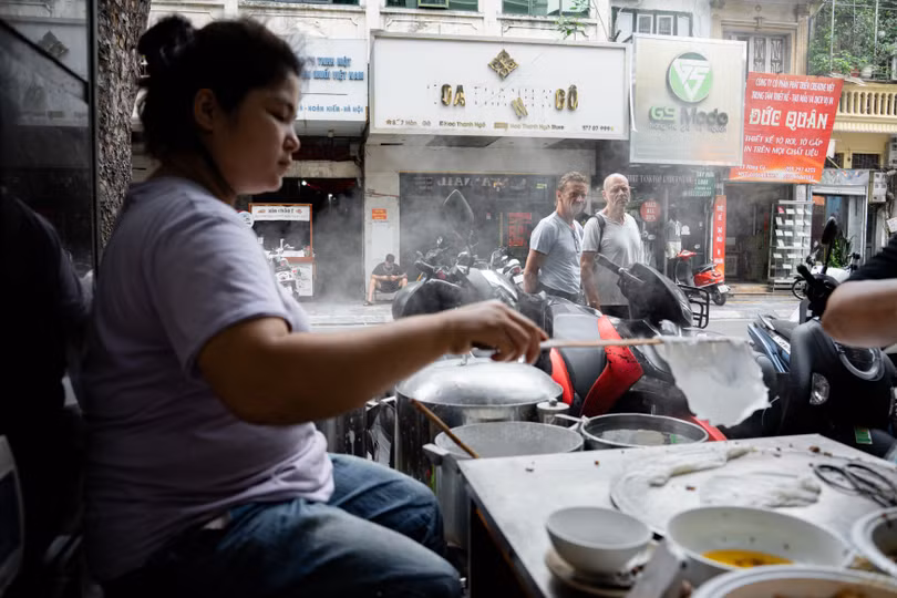 Du khách quốc tế dừng chân quan sát cách chế biến bánh cuốn ở phố cổ Hà Nội trưa 5/6. Ảnh: Trần Hiền.