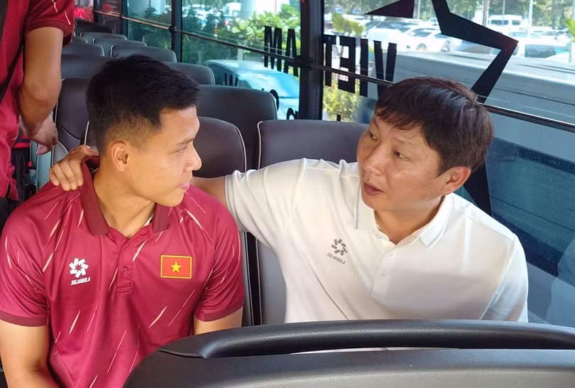 HLV Kim Sang-sik (phải) trao đổi với trung vệ Lê Ngọc Bảo trên xe buýt của đội tuyển Việt Nam, đang trên đường rời sân bay Nội Bài, Hà Nội sau khi kết thúc chuyến tập huấn tại Hàn Quốc, vào ngày 14/7/2026. Ảnh: VFF