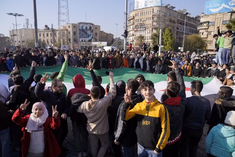 Người dân Syria mang cờ của phe đối lập ăn mừng tại Aleppo ngày 8/12.