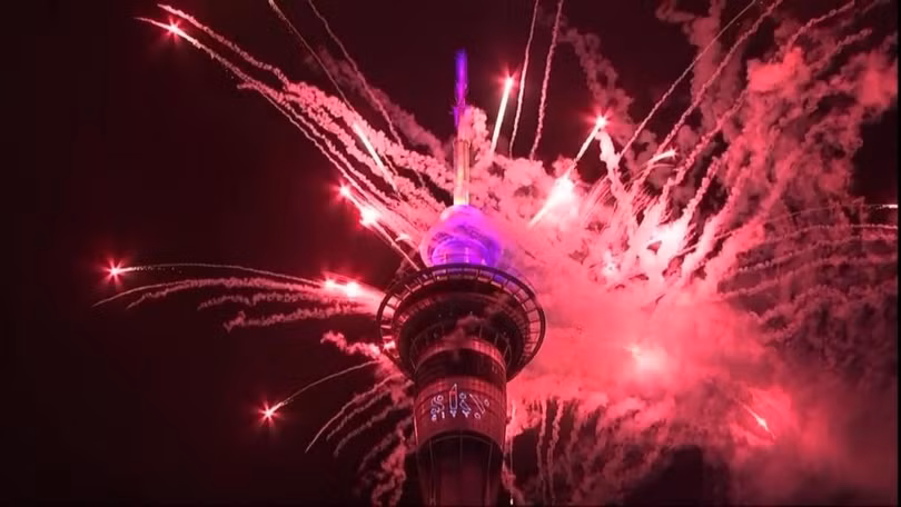 18h giờ Hà Nội: Auckland (New Zealand) trở thành thành phố lớn đầu tiên trên thế giới chào đón năm 2026. Đúng thời khắc nửa đêm, sau phần đếm ngược được chiếu trực tiếp lên tháp, màn pháo hoa kéo dài 5 phút sẽ được bắn lên từ Tháp Bầu Trời. Đây là màn pháo hoa ở độ cao lớn nhất Nam bán cầu, sử dụng hơn 500 kg pháo với 3.500 quả bắn riêng lẻ, tỏa ra theo hình vòng 360 độ từ ba tầng bắn trên tháp. Những chùm pháo vươn cao tới 80m phía trên đỉnh tháp, đạt độ cao tổng cộng khoảng 320m so với mặt đất. Ảnh: BBC.