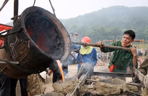 Từ sáng sớm, hàng nghìn người đã đổ về khu đúc tượng cạnh Học viện Phật giáo VN (Sóc Sơn, Hà Nội). Theo lịch âm là ngày "trùng cửu", ngày có ý nghĩa thiêng liêng đặc biệt, rất thích hợp để tiến hành đúc tượng Thánh Gióng - Đức Thánh Phù Đổng Thiên vương. Một mô hình thu nhỏ đặt cạnh khu đúc tượng để phật tử làm lễ, chiêm bái. Khi hoàn thành, tượng cao gần 11 m, độ vươn chéo lên trời khoảng 16 m. Rất nhiều người góp trang sức bằng kim loại quý để hòa cùng dòng đồng nóng chảy lúc đổ vào khuôn. Tại khu đất được cách ly cạnh đó, hai chiếc khuôn của phần đầu ngựa và thân trên Thánh Gióng đang gấp rút được hoàn tất những khâu cuối cùng. Đây là 2 thớt đầu tiên được đúc của tượng đài. Một số chi tiết khác của tượng đài cũng được làm trong mẻ đầu tiên. Hàng trăm thanh đồng đỏ nguyên chất được nung chảy trong lò ga hơn 1.000 độ C. Theo các nghệ nhân, thời gian từ lúc nấu đến lúc đổ đồng mất hơn 2 giờ. Người nghệ nhân cẩn thận trát kín mạch và tạo miệng khuôn để đổ đồng nóng chảy vào. Sau 2 giờ nung, mẻ đồng nóng chảy đổ ra... ... trong khi các nghệ nhân kính cẩn thắp hương mong mọi việc suôn sẻ. Bên ngoài hàng rào, hàng nghìn người chen lấn mong được vào chiêm ngưỡng cận cảnh. Tới dự buổi lễ sáng nay có nguyên Tổng bí thư Đỗ Mười, cùng nhiều vị lãnh đạo. Ngay trước thời khắc 9h9, hòa thượng Thích Thanh Tứ, Phó chủ tịch Trung ương hội Phật giáo VN(người đeo tràng hạt) cùng nhiều quan chức tiến vào khu đúc tượng. Hàng trăm món đồ kim loại quý được thả vào khuôn... ... trước khi dòng đồng đỏ nóng chảy được rót. Theo các nghệ nhân, công đoạn khó nhất của quá trình đúc tượng là khâu làm khuôn: mất 2 tháng. Khuôn phải làm sao để toát lên được thần thái của Thánh Gióng và toàn bộ hoa văn, họa tiết tinh xảo của tượng với đúng tỉ lệ 1:1. Sau khi đổ đầy đồng vào khuôn, cần tới 4 ngày để làm nguội tự nhiên rồi mới phá khuôn.