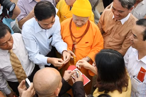 Từ sáng sớm, hàng nghìn người đã đổ về khu đúc tượng cạnh Học viện Phật giáo VN (Sóc Sơn, Hà Nội). Theo lịch âm là ngày "trùng cửu", ngày có ý nghĩa thiêng liêng đặc biệt, rất thích hợp để tiến hành đúc tượng Thánh Gióng - Đức Thánh Phù Đổng Thiên vương. Một mô hình thu nhỏ đặt cạnh khu đúc tượng để phật tử làm lễ, chiêm bái. Khi hoàn thành, tượng cao gần 11 m, độ vươn chéo lên trời khoảng 16 m. Rất nhiều người góp trang sức bằng kim loại quý để hòa cùng dòng đồng nóng chảy lúc đổ vào khuôn. Tại khu đất được cách ly cạnh đó, hai chiếc khuôn của phần đầu ngựa và thân trên Thánh Gióng đang gấp rút được hoàn tất những khâu cuối cùng. Đây là 2 thớt đầu tiên được đúc của tượng đài. Một số chi tiết khác của tượng đài cũng được làm trong mẻ đầu tiên. Hàng trăm thanh đồng đỏ nguyên chất được nung chảy trong lò ga hơn 1.000 độ C. Theo các nghệ nhân, thời gian từ lúc nấu đến lúc đổ đồng mất hơn 2 giờ. Người nghệ nhân cẩn thận trát kín mạch và tạo miệng khuôn để đổ đồng nóng chảy vào. Sau 2 giờ nung, mẻ đồng nóng chảy đổ ra... ... trong khi các nghệ nhân kính cẩn thắp hương mong mọi việc suôn sẻ. Bên ngoài hàng rào, hàng nghìn người chen lấn mong được vào chiêm ngưỡng cận cảnh. Tới dự buổi lễ sáng nay có nguyên Tổng bí thư Đỗ Mười, cùng nhiều vị lãnh đạo. Ngay trước thời khắc 9h9, hòa thượng Thích Thanh Tứ, Phó chủ tịch Trung ương hội Phật giáo VN(người đeo tràng hạt) cùng nhiều quan chức tiến vào khu đúc tượng. Hàng trăm món đồ kim loại quý được thả vào khuôn... ... trước khi dòng đồng đỏ nóng chảy được rót. Theo các nghệ nhân, công đoạn khó nhất của quá trình đúc tượng là khâu làm khuôn: mất 2 tháng. Khuôn phải làm sao để toát lên được thần thái của Thánh Gióng và toàn bộ hoa văn, họa tiết tinh xảo của tượng với đúng tỉ lệ 1:1. Sau khi đổ đầy đồng vào khuôn, cần tới 4 ngày để làm nguội tự nhiên rồi mới phá khuôn.