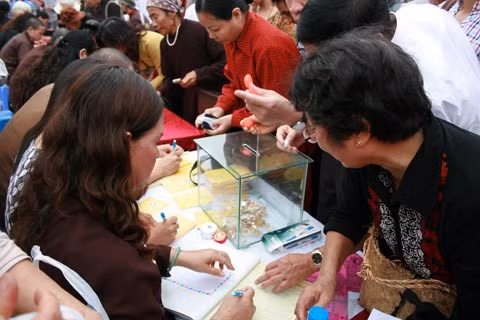 Từ sáng sớm, hàng nghìn người đã đổ về khu đúc tượng cạnh Học viện Phật giáo VN (Sóc Sơn, Hà Nội). Theo lịch âm là ngày "trùng cửu", ngày có ý nghĩa thiêng liêng đặc biệt, rất thích hợp để tiến hành đúc tượng Thánh Gióng - Đức Thánh Phù Đổng Thiên vương. Một mô hình thu nhỏ đặt cạnh khu đúc tượng để phật tử làm lễ, chiêm bái. Khi hoàn thành, tượng cao gần 11 m, độ vươn chéo lên trời khoảng 16 m. Rất nhiều người góp trang sức bằng kim loại quý để hòa cùng dòng đồng nóng chảy lúc đổ vào khuôn. Tại khu đất được cách ly cạnh đó, hai chiếc khuôn của phần đầu ngựa và thân trên Thánh Gióng đang gấp rút được hoàn tất những khâu cuối cùng. Đây là 2 thớt đầu tiên được đúc của tượng đài. Một số chi tiết khác của tượng đài cũng được làm trong mẻ đầu tiên. Hàng trăm thanh đồng đỏ nguyên chất được nung chảy trong lò ga hơn 1.000 độ C. Theo các nghệ nhân, thời gian từ lúc nấu đến lúc đổ đồng mất hơn 2 giờ. Người nghệ nhân cẩn thận trát kín mạch và tạo miệng khuôn để đổ đồng nóng chảy vào. Sau 2 giờ nung, mẻ đồng nóng chảy đổ ra... ... trong khi các nghệ nhân kính cẩn thắp hương mong mọi việc suôn sẻ. Bên ngoài hàng rào, hàng nghìn người chen lấn mong được vào chiêm ngưỡng cận cảnh. Tới dự buổi lễ sáng nay có nguyên Tổng bí thư Đỗ Mười, cùng nhiều vị lãnh đạo. Ngay trước thời khắc 9h9, hòa thượng Thích Thanh Tứ, Phó chủ tịch Trung ương hội Phật giáo VN(người đeo tràng hạt) cùng nhiều quan chức tiến vào khu đúc tượng. Hàng trăm món đồ kim loại quý được thả vào khuôn... ... trước khi dòng đồng đỏ nóng chảy được rót. Theo các nghệ nhân, công đoạn khó nhất của quá trình đúc tượng là khâu làm khuôn: mất 2 tháng. Khuôn phải làm sao để toát lên được thần thái của Thánh Gióng và toàn bộ hoa văn, họa tiết tinh xảo của tượng với đúng tỉ lệ 1:1. Sau khi đổ đầy đồng vào khuôn, cần tới 4 ngày để làm nguội tự nhiên rồi mới phá khuôn.