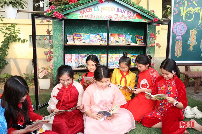 Các em học sinh đọc sách bên các tủ sách ngoài trời được làm từ các vật liệu tái chế.